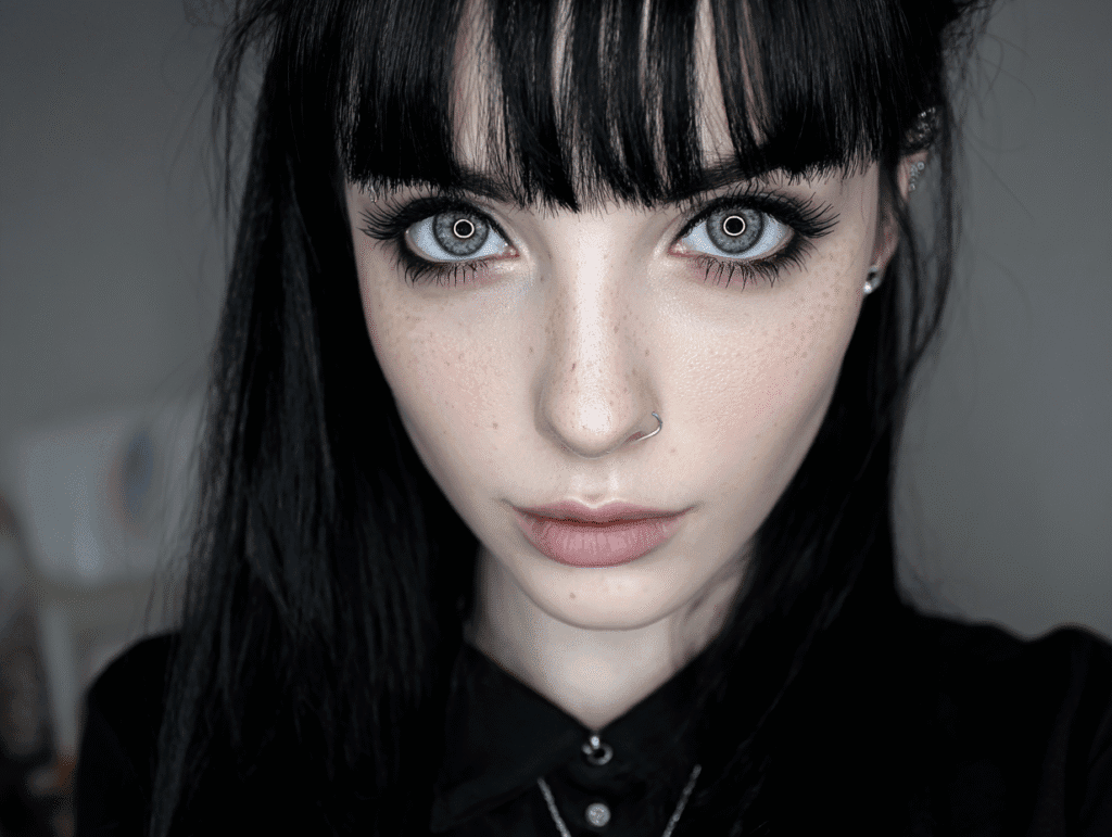 Alternative gothic woman with intense light blue eyes and black hair showing magnetic presence
